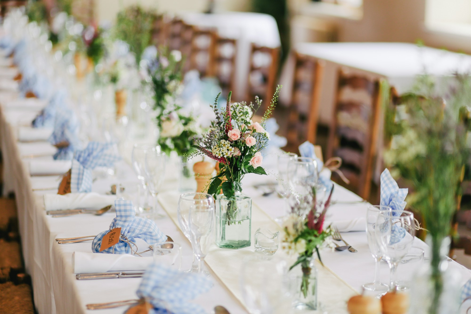 An elegant garden reception with flowers, chandeliers and beautifully set tables